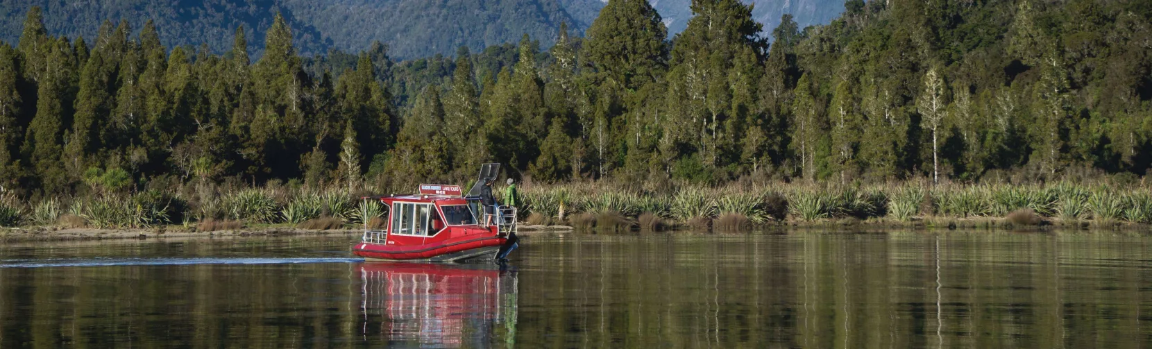 Scenic Cruise boat on Lake Mapourika with the Southern Alps in the background near Franz Josef, West Coast New Zealand
