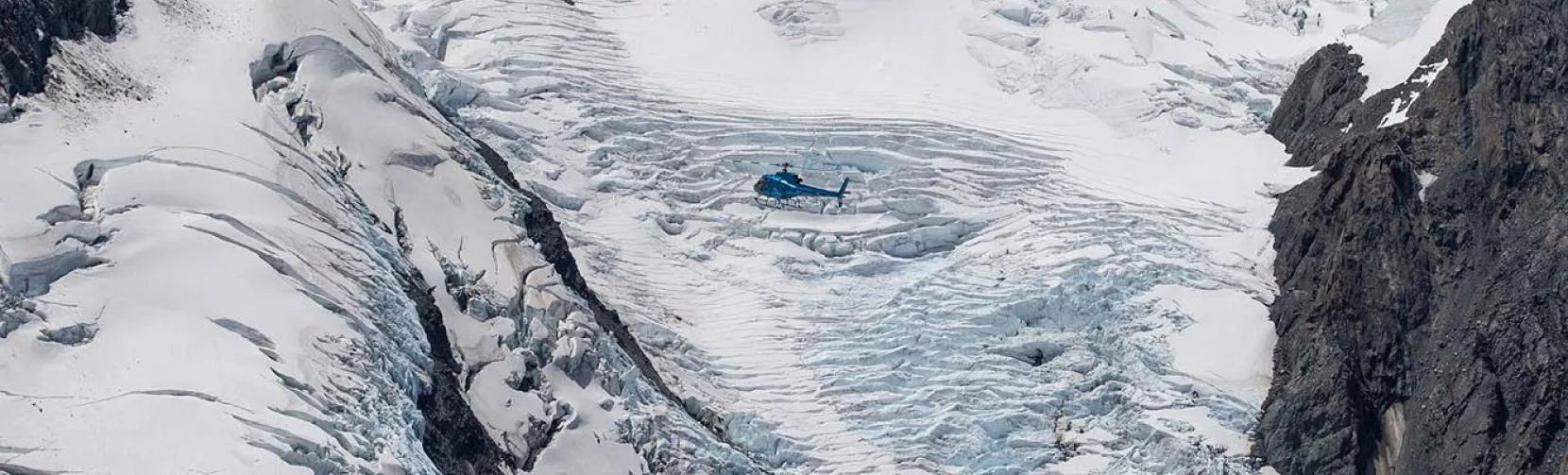 GCH Squirrel helicopter flying over Franz Josef Glacier’s icy terrain in New Zealand