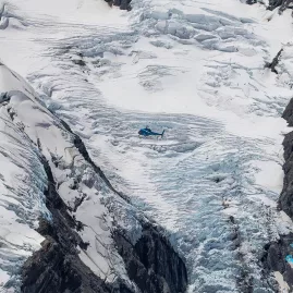 GCH Squirrel helicopter flying over Franz Josef Glacier’s icy terrain in New Zealand