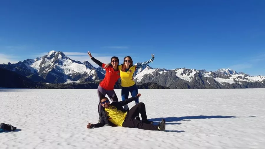 Three smiling people posing on the snow during a Middleton landing near Franz Josef with Glacier Country Helicopters