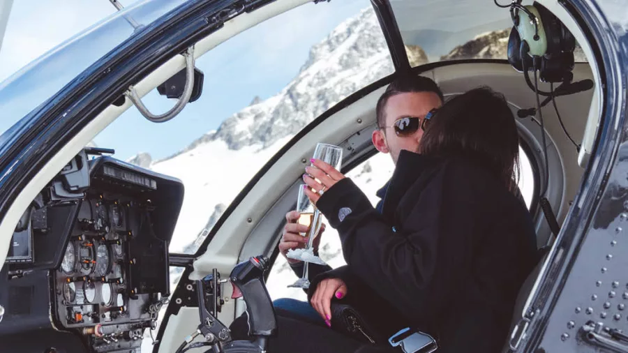 Couple sharing a kiss inside a Glacier Country Helicopter with champagne