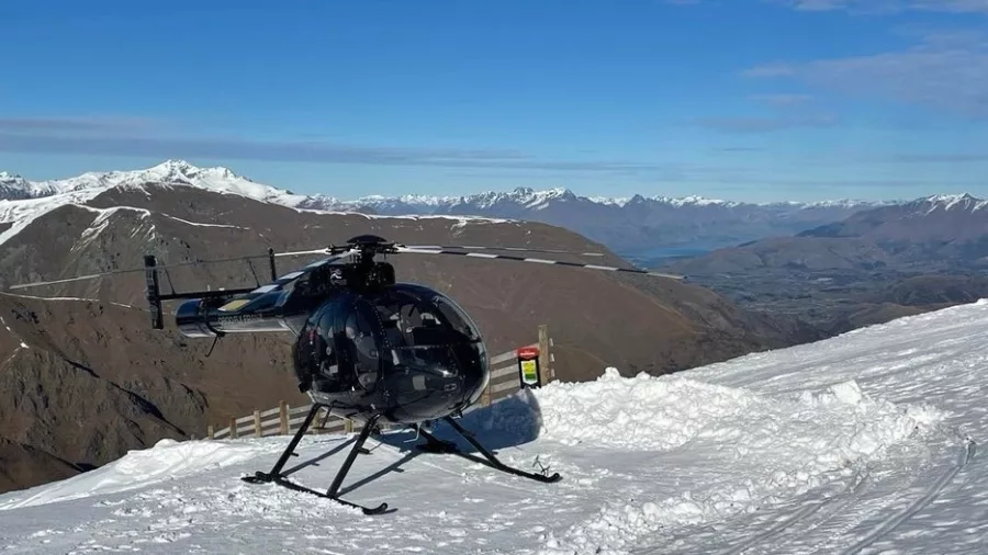Helicopter landed on a snowy mountain ridge during a South Westland scenic adventure