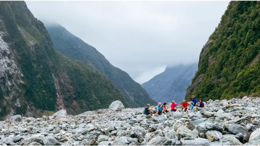 Small group resting in a glacier valley surrounded by steep cliffs on New Zealand’s West Coast