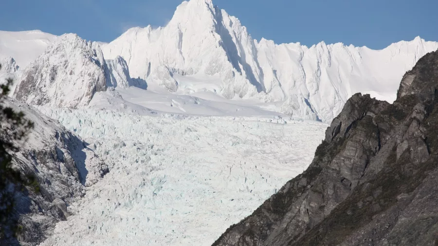Snow-covered summit of Mount Tasman surrounded by rugged peaks on New Zealand’s West Coast