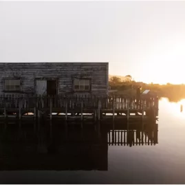 Historic boathouse at Okarito Lagoon during sunrise, West Coast New Zealand