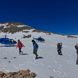 Travellers walk on snow after a helicopter landing in the Southern Alps from Franz Josef