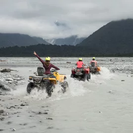 Riders on quad bikes crossing glacial rivers near Franz Josef Glacier on New Zealand’s West Coast