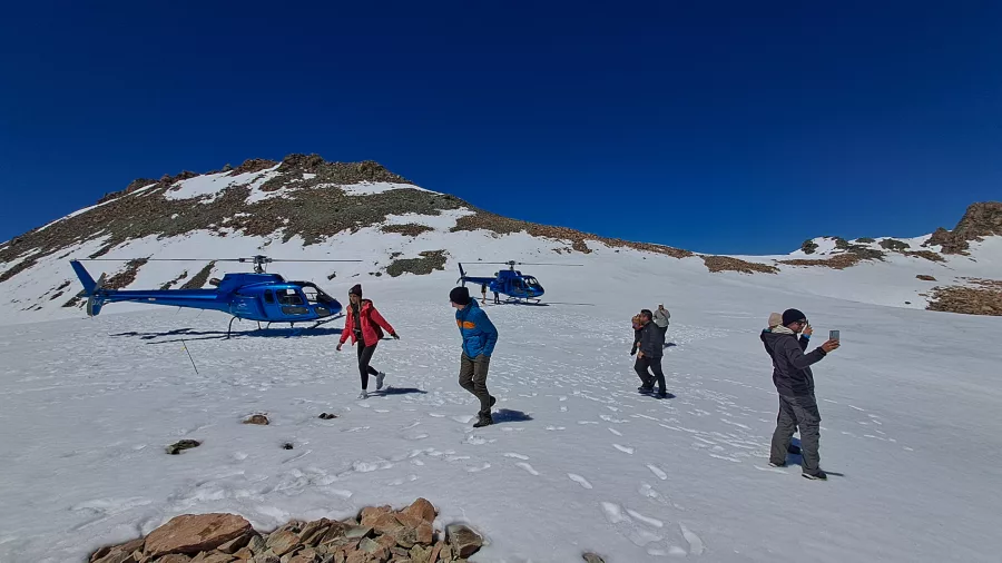 Travellers walk on snow after a helicopter landing in the Southern Alps from Franz Josef