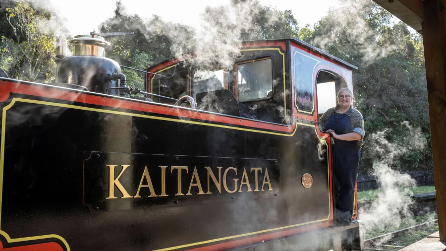 Steam engine Kaitangata at Shantytown Heritage Park in Greymouth with a smiling engineer standing by the cabin.