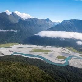 Aerial view of the braided Haast River winding through lush valleys and dramatic alpine ranges on the West Coast of New Zealand