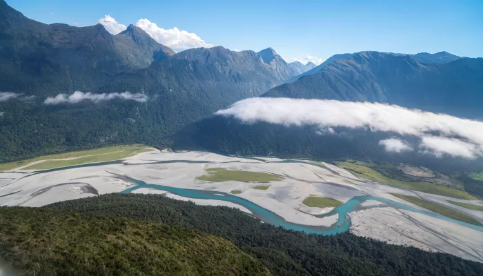 Aerial view of the braided Haast River winding through lush valleys and dramatic alpine ranges on the West Coast of New Zealand