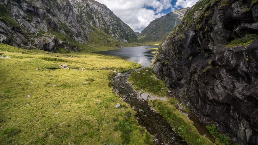 Panoramic view of a valley and alpine lake in Haast UNESCO World Heritage Area, New Zealand