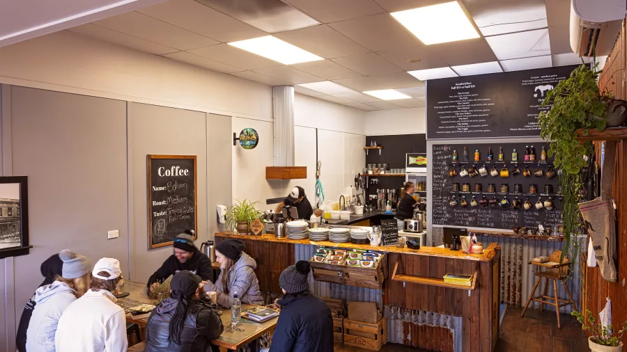 Interior of the Hokitika Sandwich Company with staff preparing food and diners seated at rustic wooden tables