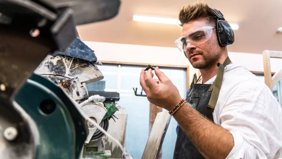 Jade carver at Bonz ‘N’ Stonz studio in Hokitika holding a carved piece