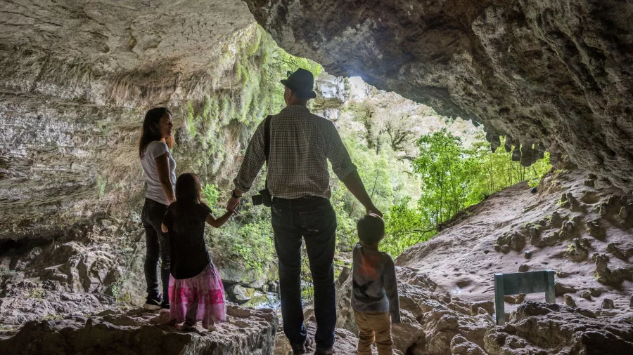 Family standing at the entrance of Ōpārara Arches in Karamea, West Coast