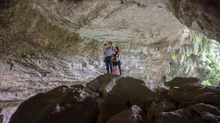 Family standing on boulders inside Ōpārara Arches in Karamea, West Coast