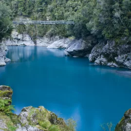 Suspension bridge crossing Hokitika Gorge with vivid blue glacial water below