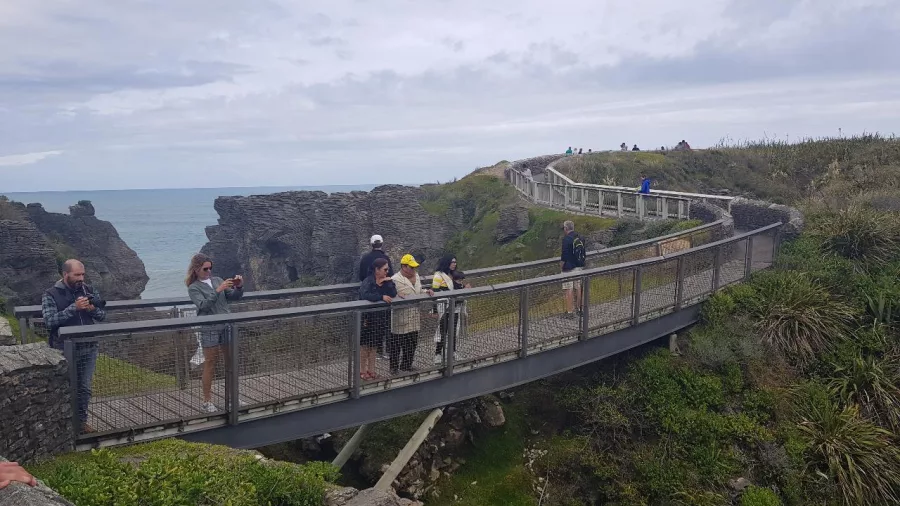 Visitors walking along the viewing track at Punakaiki, surrounded by rock formations and sea views