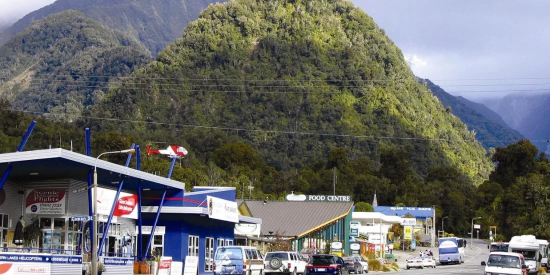 Scenic view of Franz Josef township with lush West Coast hills in the background