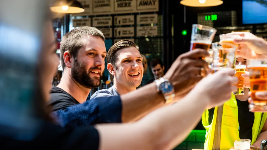 Group of friends toasting with beers at Monteith’s Brewery in Greymouth