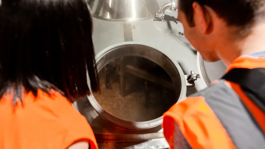 Visitors peering into brewing equipment at Monteith’s Brewery tour