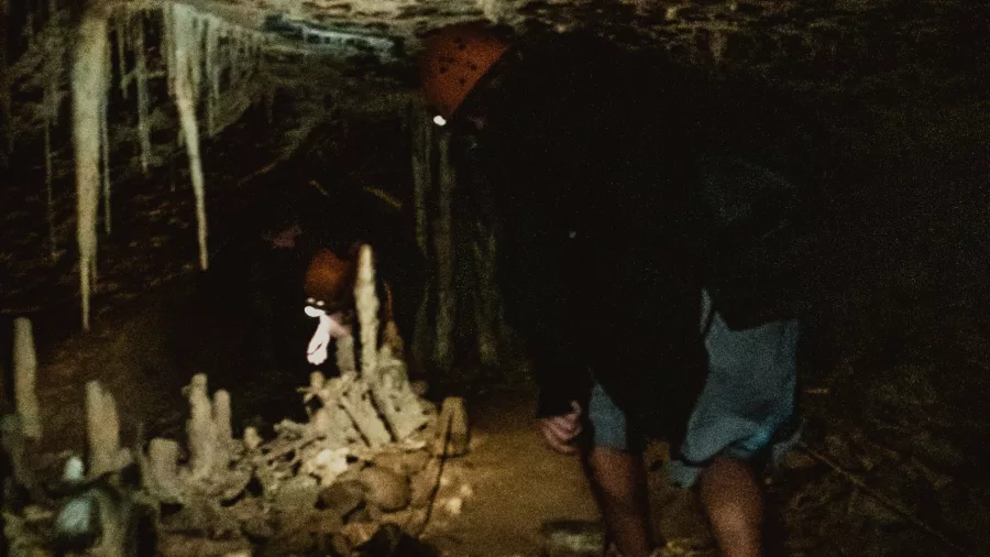 Travellers crawl through a narrow limestone passage during the Glow Worm Cave Tour with Underworld Adventures in Charleston, New Zealand