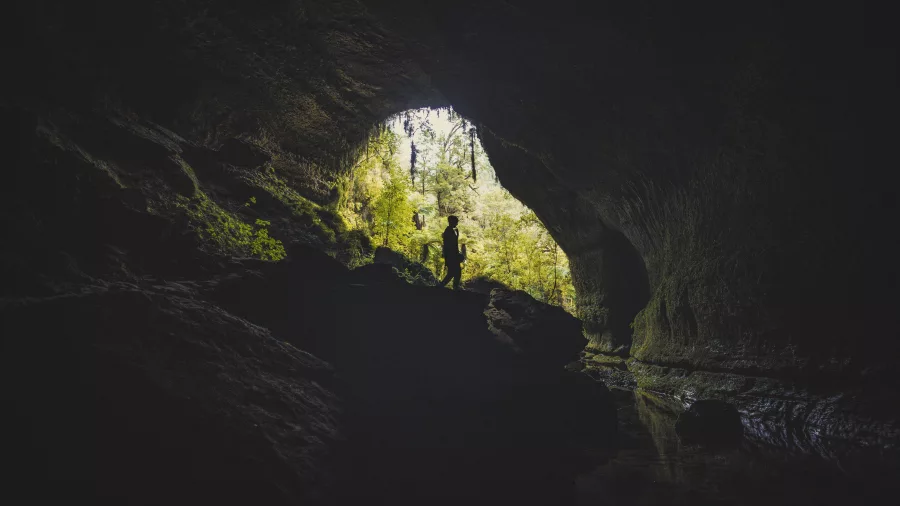 Silhouetted explorer at the entrance of Underworld Adventures cave in Charleston, West Coast NZ