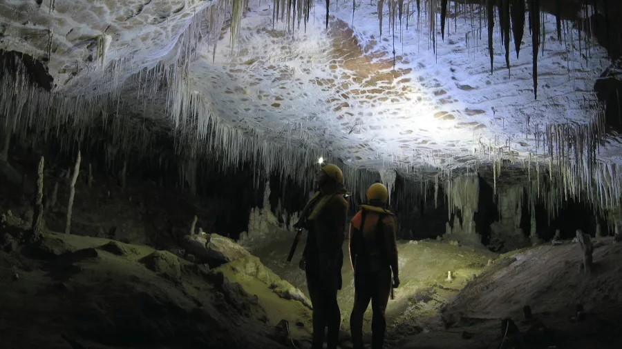 Two adventurers explore a glow-lit limestone cave with Underworld Adventures in Charleston