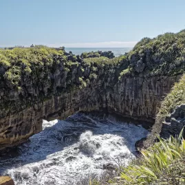 Waves crashing through natural sea arches at the Punakaiki Blowholes in Paparoa National Park