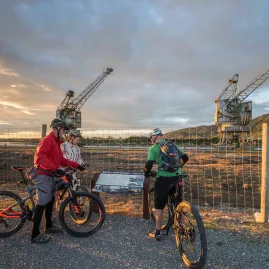 Cyclists stop by the historic Cowans Sheldon cranes at Coal River Park on the West Coast Wilderness Trail in Greymouth