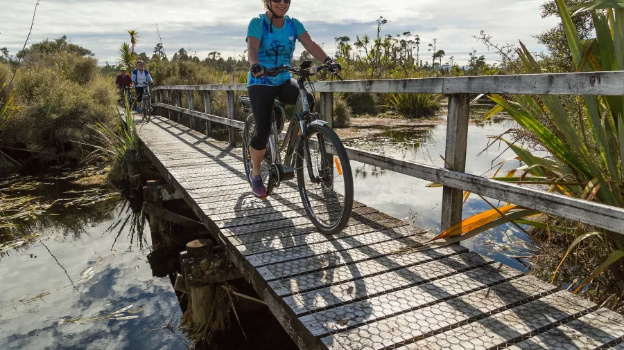 Cyclists crossing the Mahinapua Creek boardwalk on the West Coast Wilderness Trail