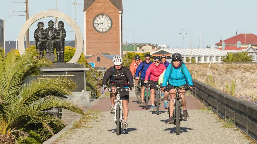 Cyclists passing the Miners Memorial and clocktower on the Greymouth Floodwall section of the West Coast Wilderness Trail