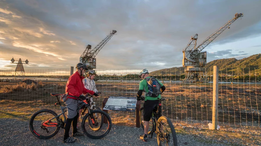 Cyclists stop by the historic Cowans Sheldon cranes at Coal River Park on the West Coast Wilderness Trail in Greymouth