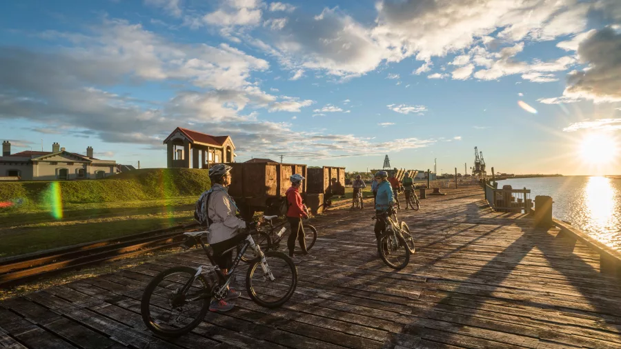 Cyclists stop to explore mining carts and heritage displays at Coal River Park on the West Coast Wilderness Trail