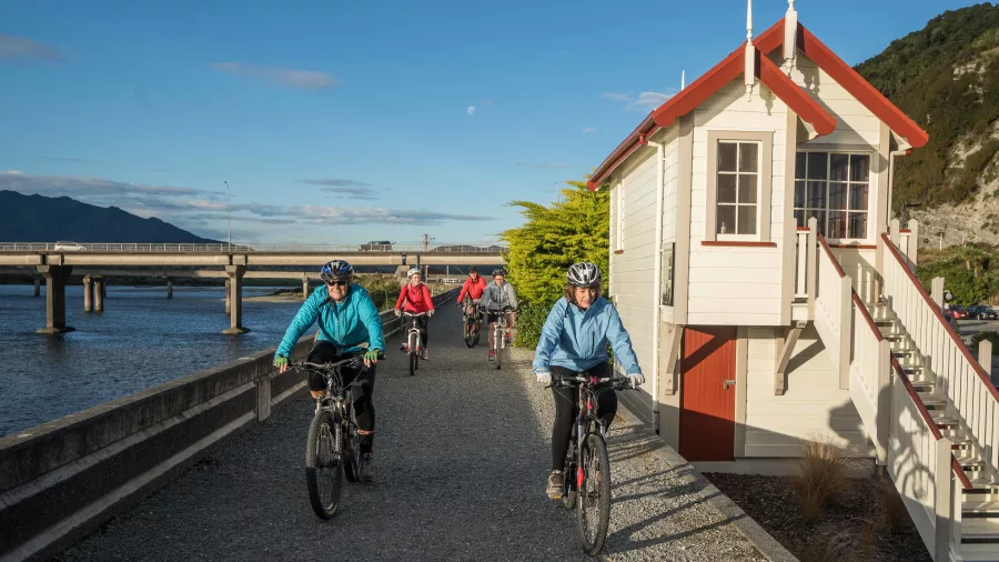 Group of cyclists passing the restored signal box on Greymouth Floodwall along the West Coast Wilderness Trail