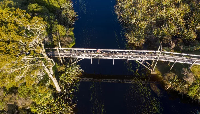 Cyclist crossing the wooden bridge over Māhinapua Creek near Hokitika on the West Coast Wilderness Trail