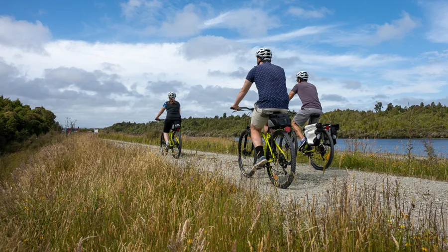 Cyclists riding along the West Coast Wilderness Trail near Greymouth on a clear day
