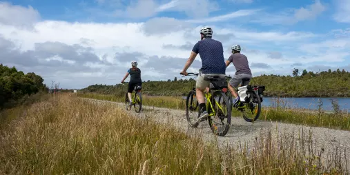 Cyclists riding along the West Coast Wilderness Trail near Greymouth on a clear day